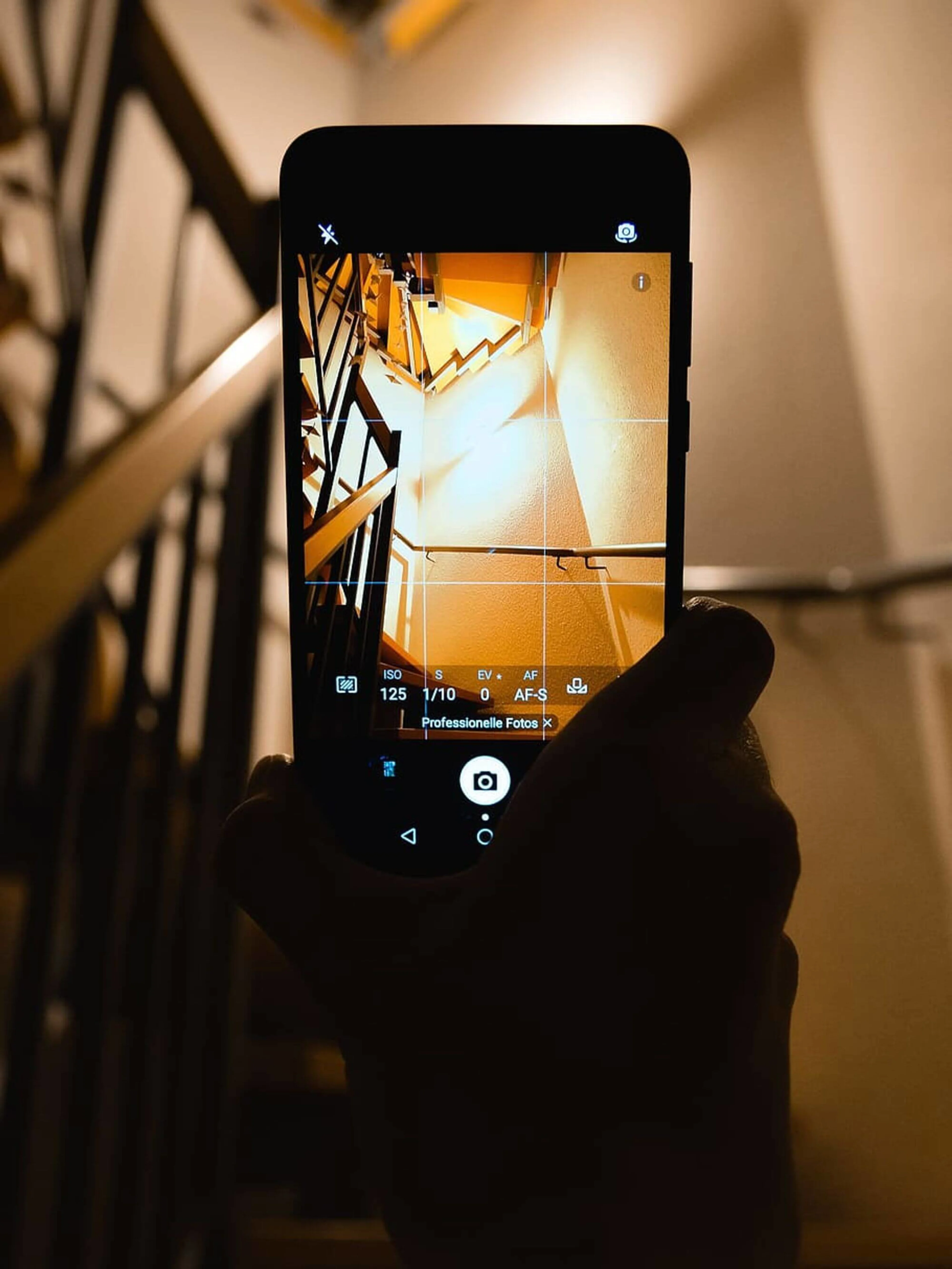 A woman taking a picture of a staircase.