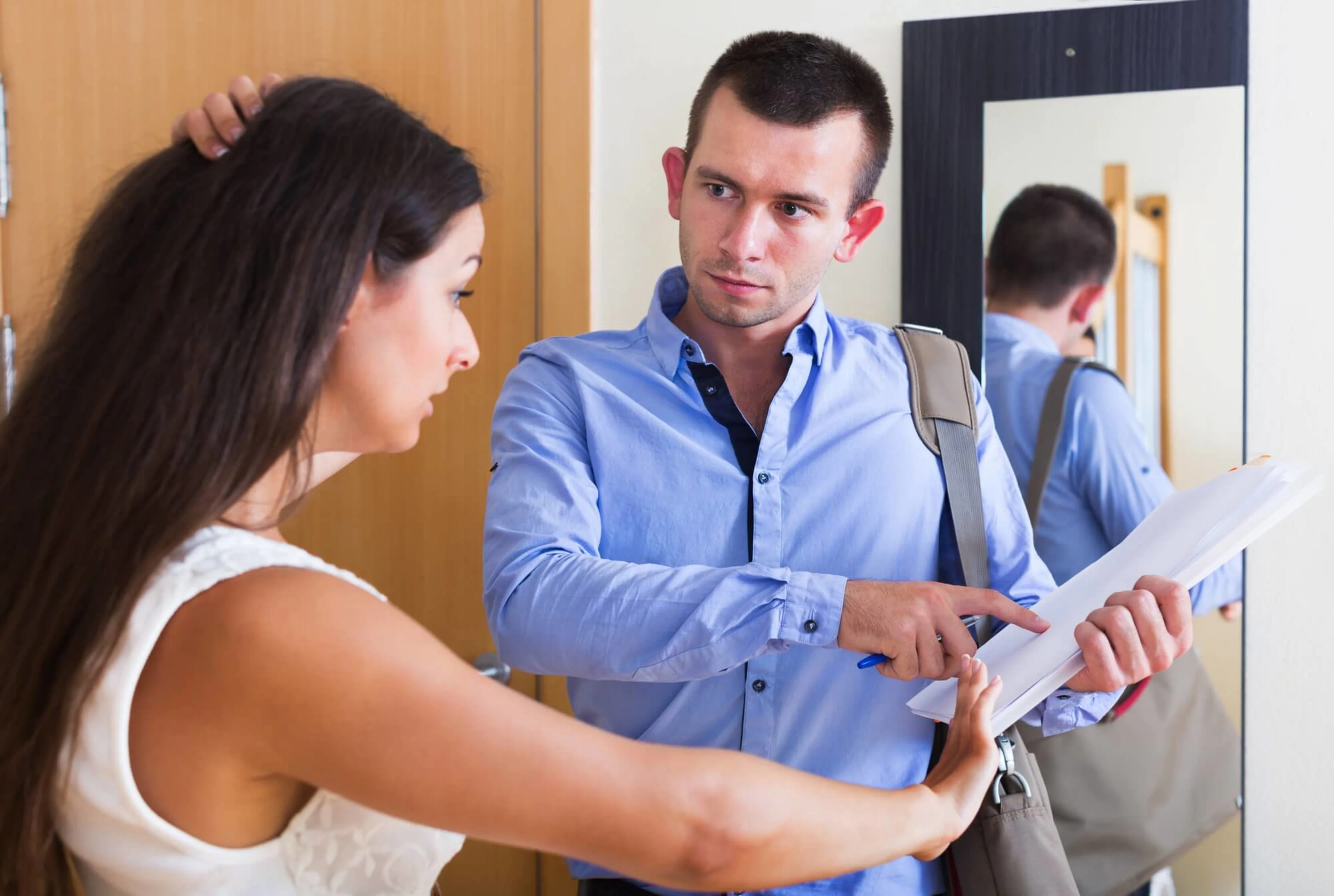 A leasing agent pointing at a tenancy agreement, whilst the tenant looks overwhelmed.