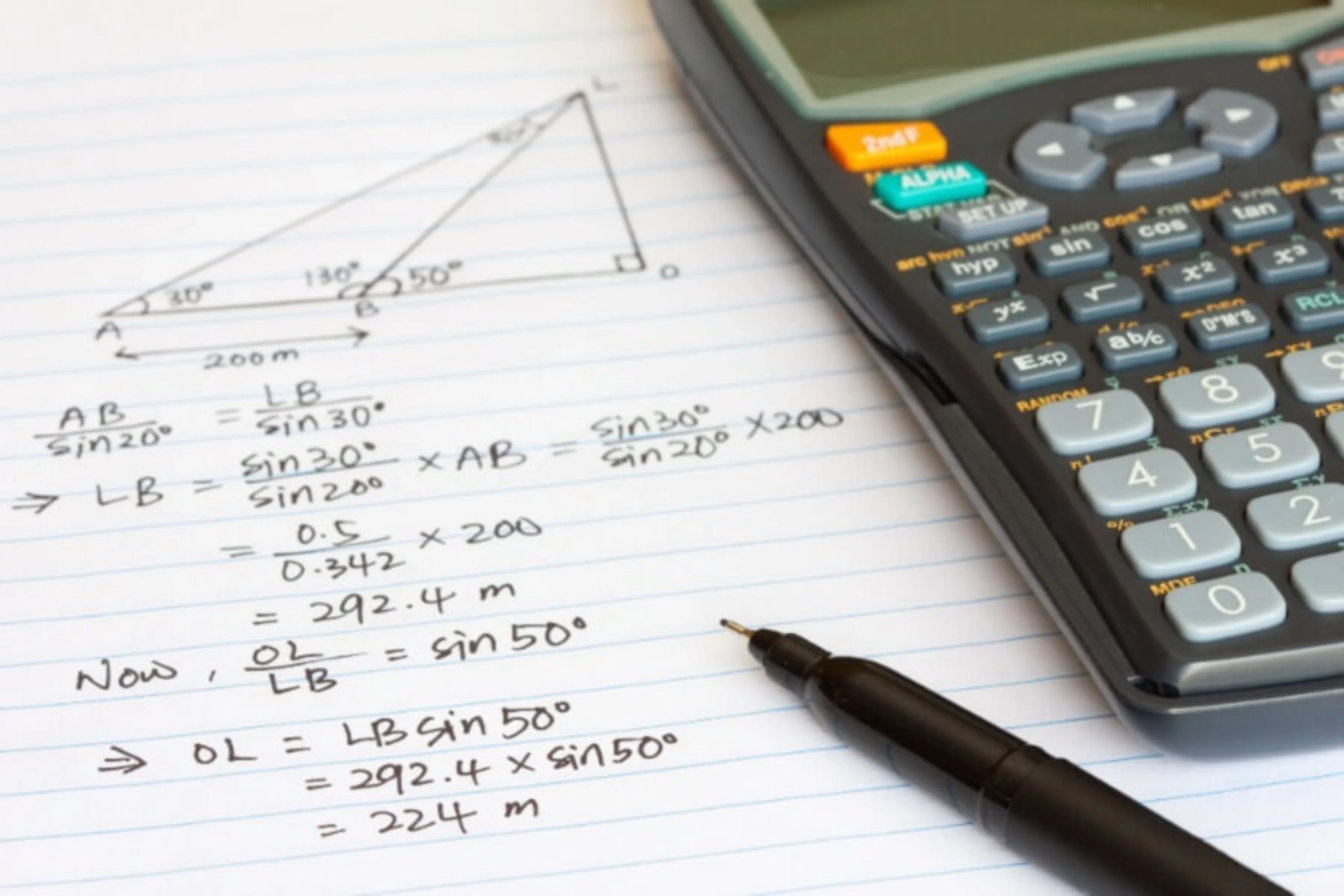 Math calculations written on a piece of paper by hand. A triangle is drawn and the calculations show the use of trigonometric functions to calculate a length of the triangle's side