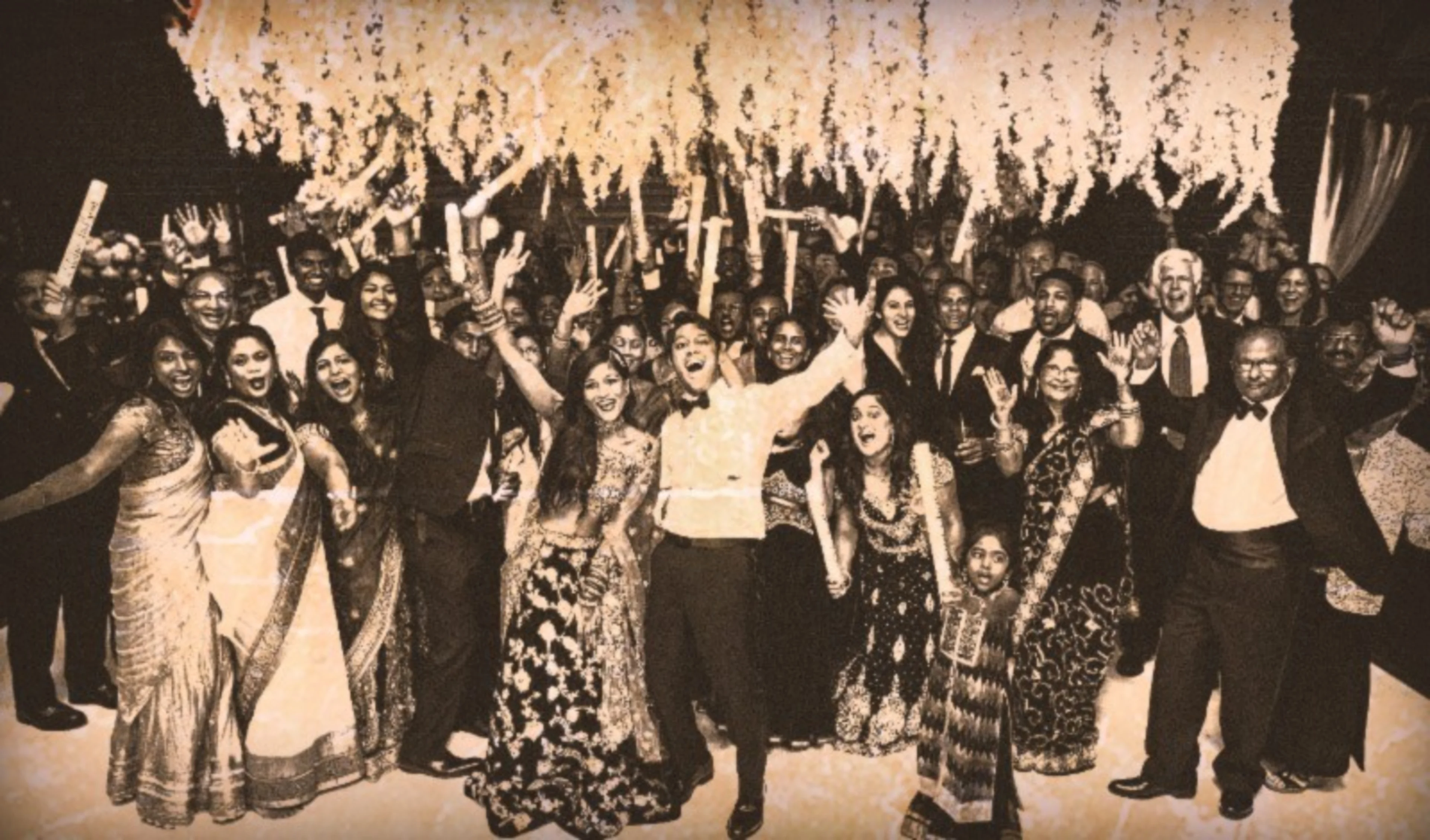 An old photograph of several participants at an Indian function. Many of the male guests are wearing British suit attire.