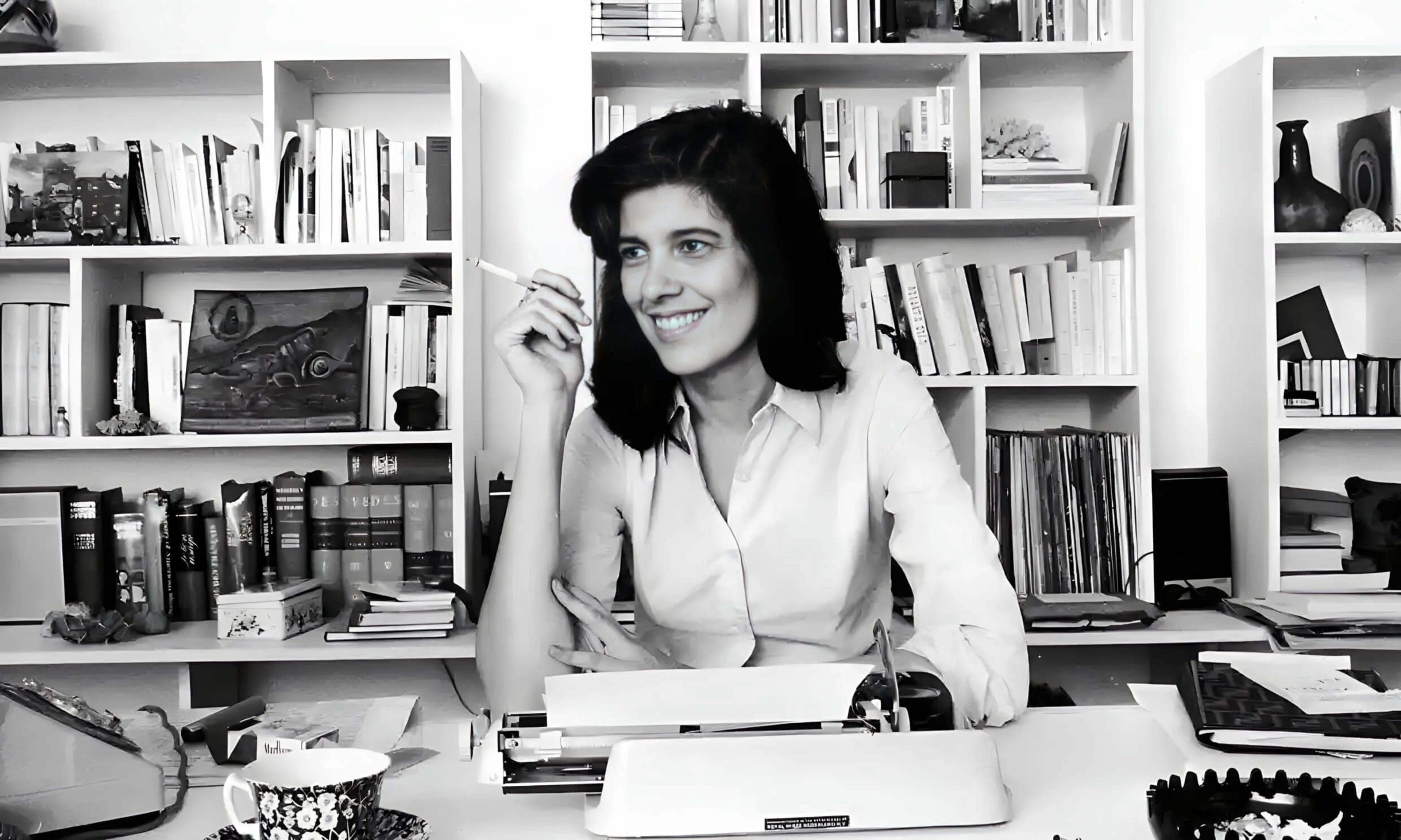 A photograph of Susan Sontag in 1972 sat at her desk in front of a typewriter.