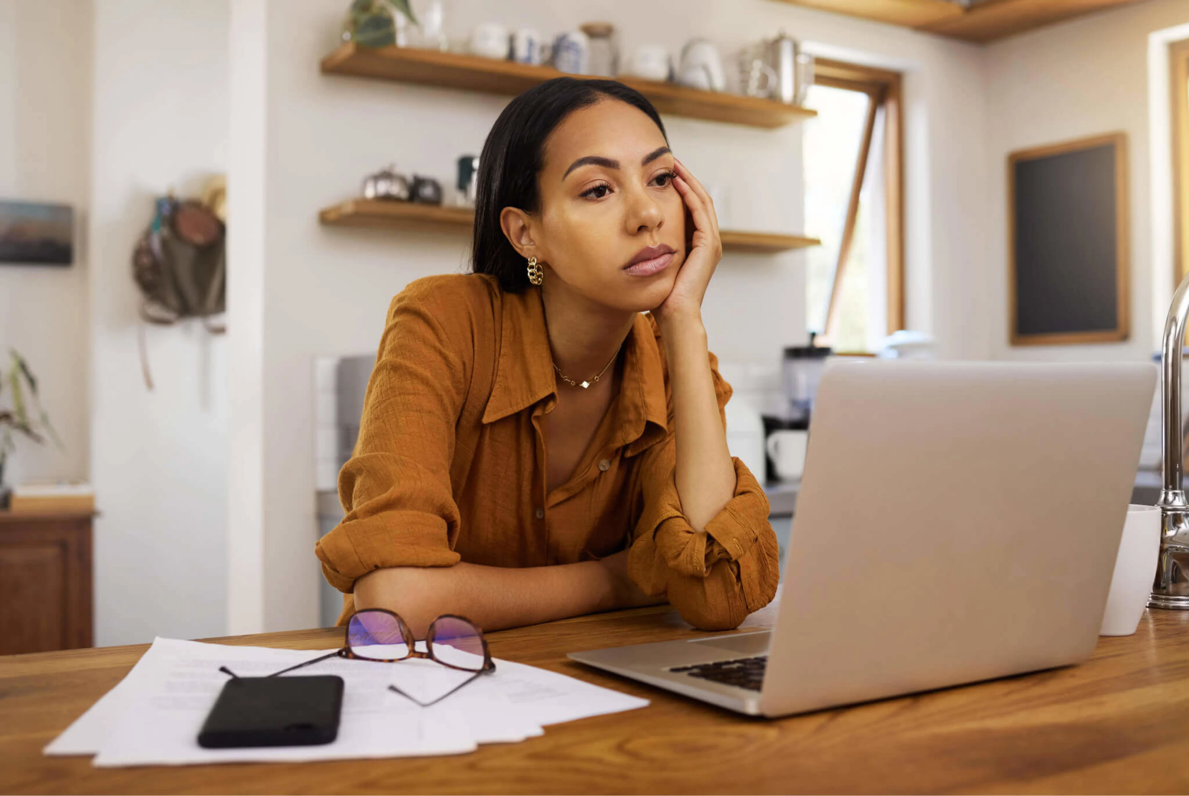 A young woman sits at her desk whilst working from home, bored and unenthused