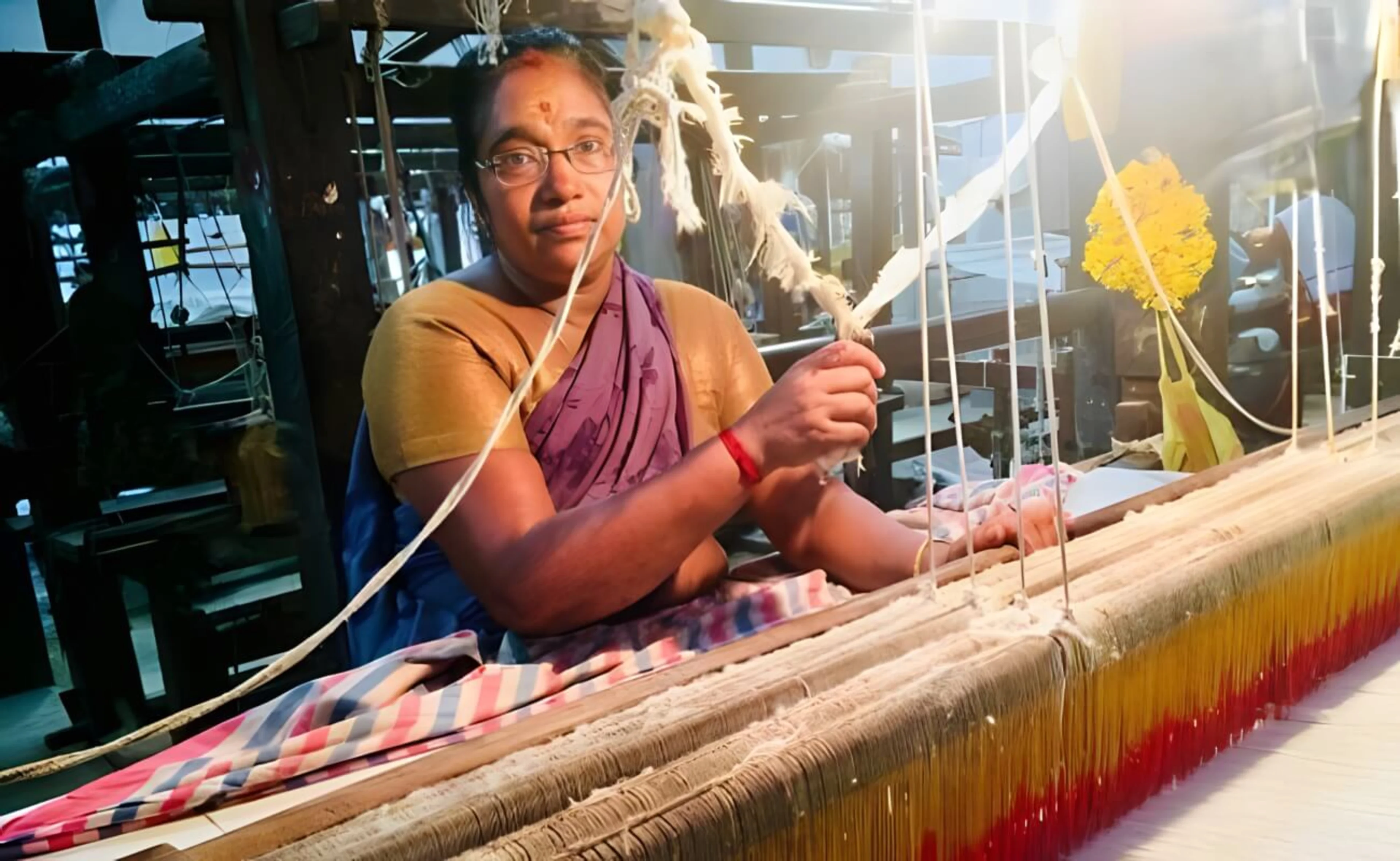 A middle-aged woman operating the handloom in a factory in Kerala, India