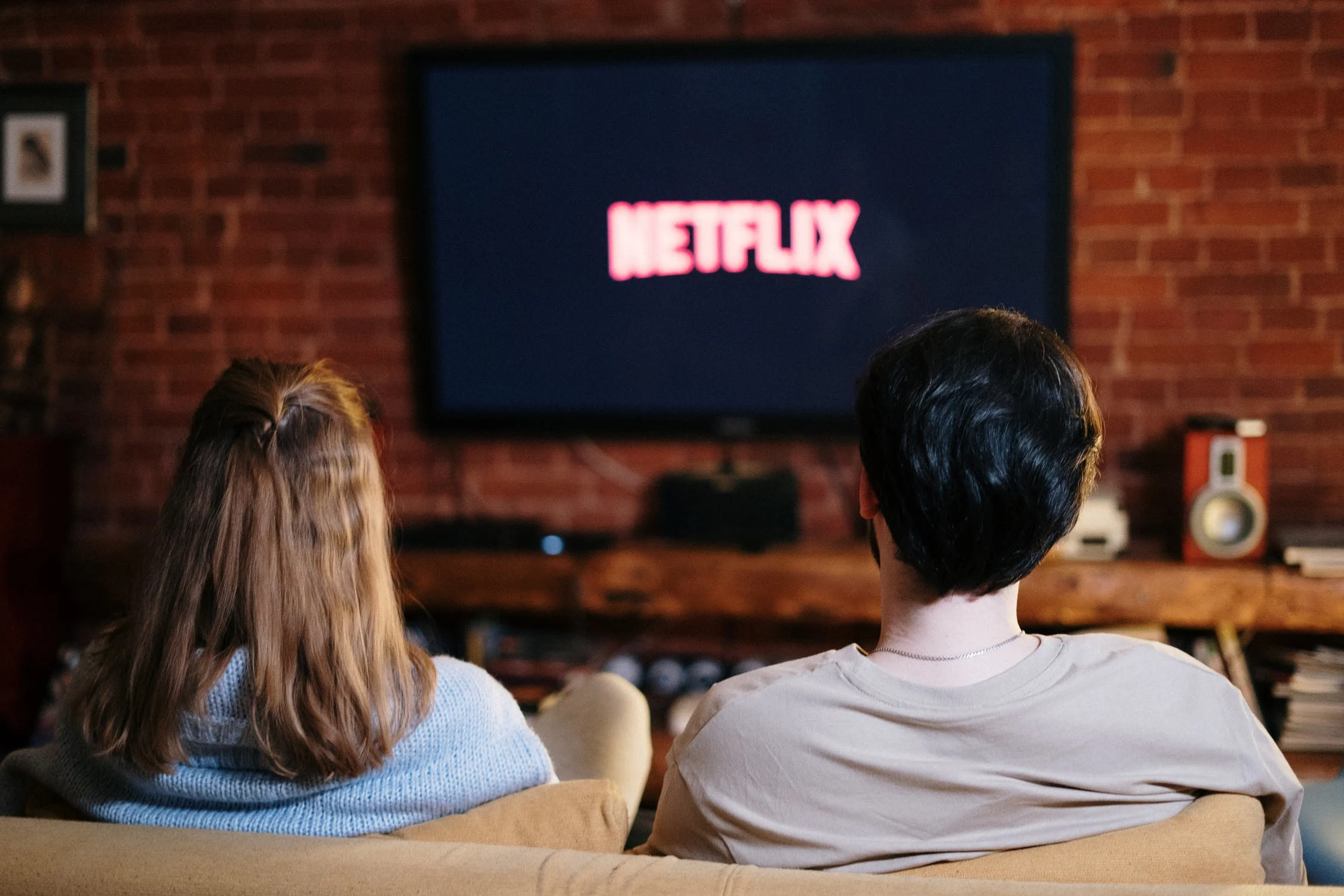 A man and a woman sitting on a couch watching Netflix