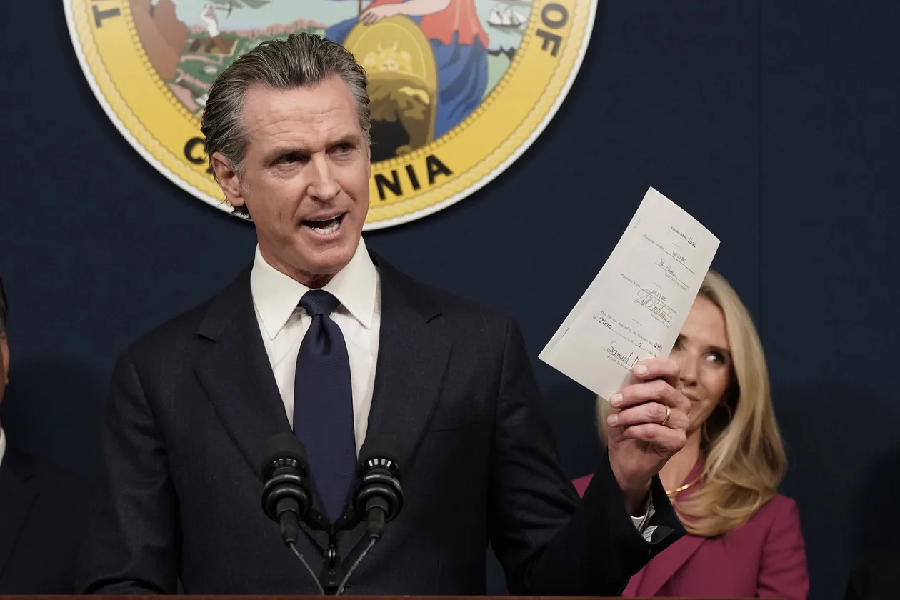 During a press conference in Sacramento, California, Gavin Newsom shows a recently signed bill protecting abortion providers and volunteers from legal judgments from out-of-state courts.