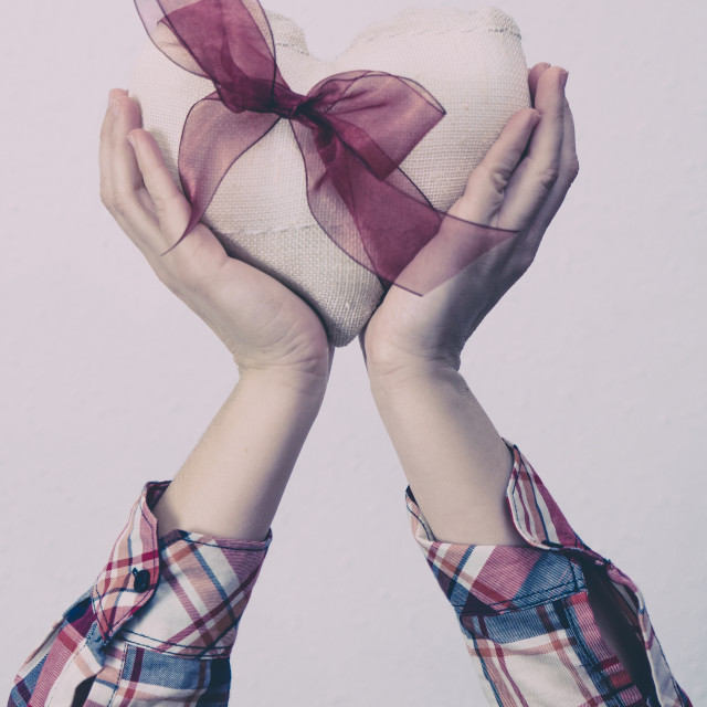 "Hands holding a white fabric heart with a red ribbon" stock image