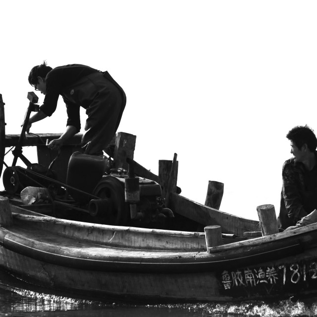 "Two Chinese fishermen bring the boat in to moore on the beach" stock image