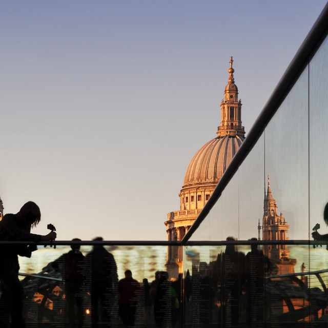 "Tourists at dusk on Millennium Bridge, with a detail of St Paul's Cathedral..." stock image