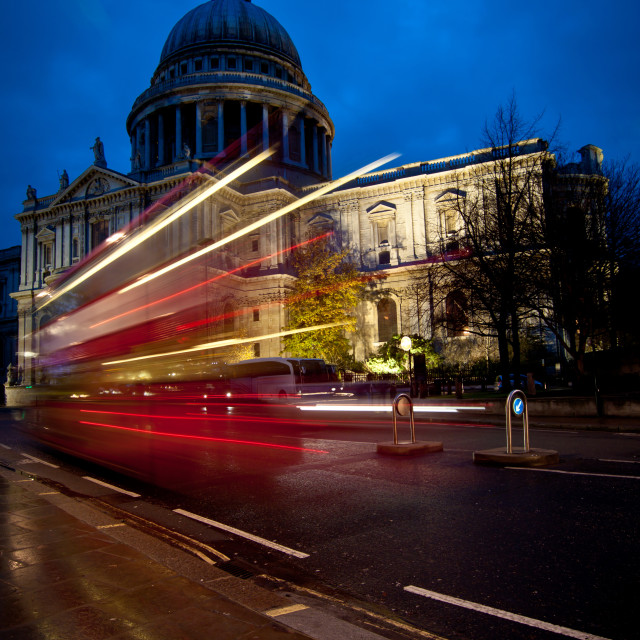 "A red double decker bus speeding past St Paul's cathedral, London, at dusk." stock image