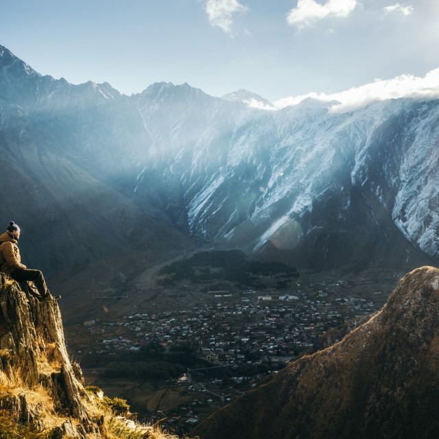 "Backpacker sit on cliff edge and looks at mount valley" stock image