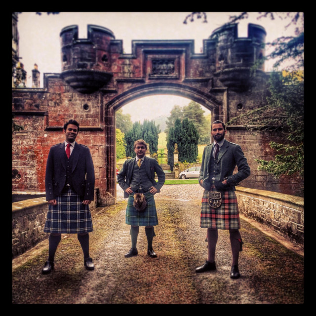 "Men dressed in kilts stand outside a castle in Scotland" stock image