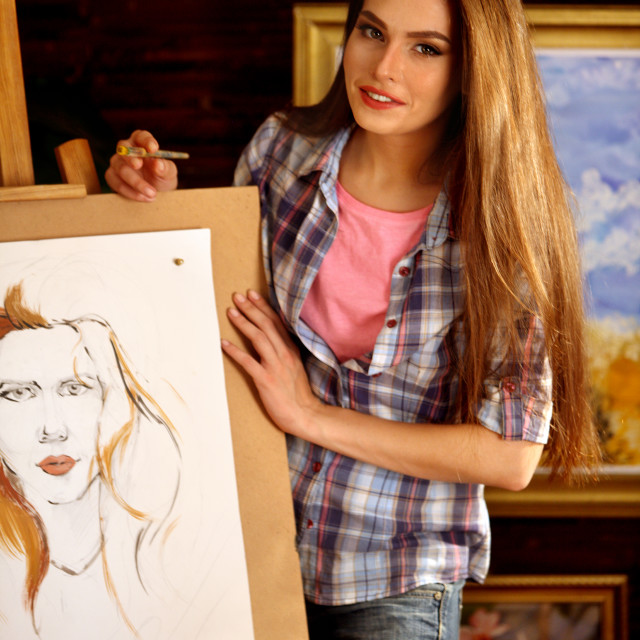 "Artist painting on easel in studio. Girl paints portrait of woman with brush." stock image