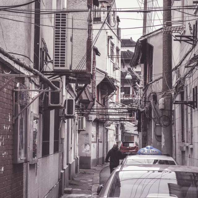 "Tight back alley with criss-crossing power lines" stock image