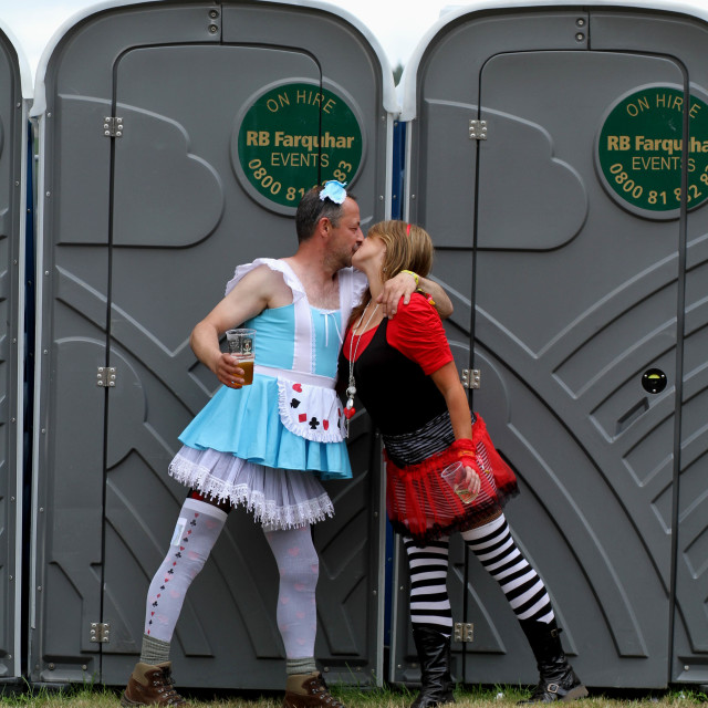 "Two people in fancy dress kissing in front of a Portaloo" stock image