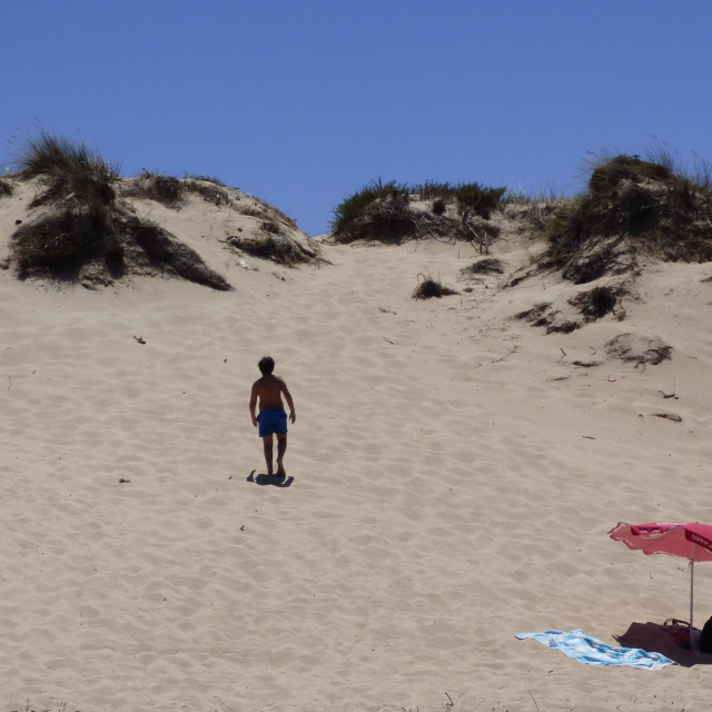 "boy on the beach climbing the dune" stock image