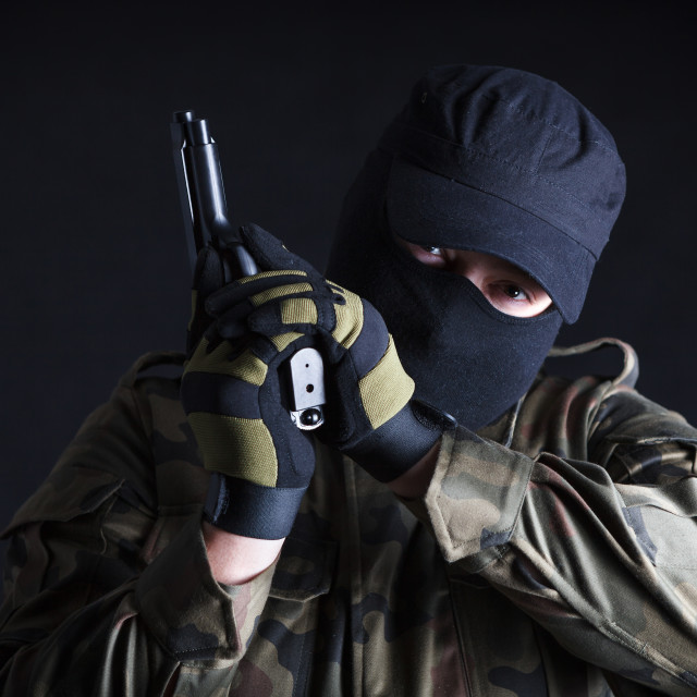 "Anti terrorist holding a gun, looking at camera on black background" stock image