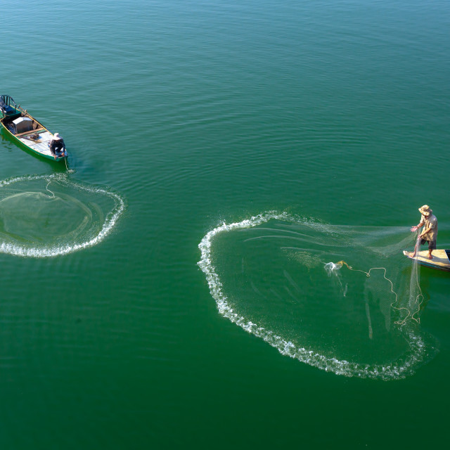 "Two men cast their nets fishing on the Tri An reservoir" stock image
