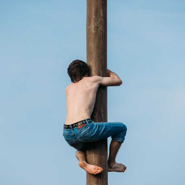 "GOMEL, BELARUS - February 21, 2014: Young man climbs on a wooden post on..." stock image