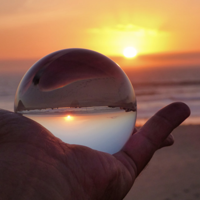 "holding a crystal ball at sunset on the beach" stock image