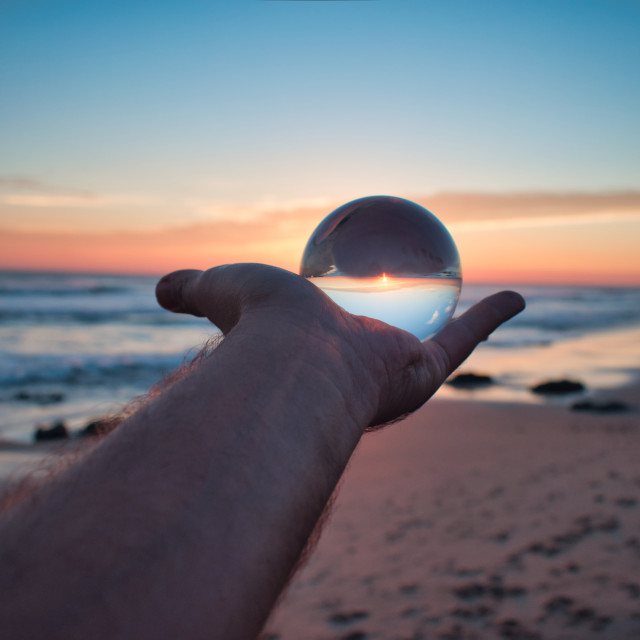 "Cristal ball on hand at sunset on the beach" stock image