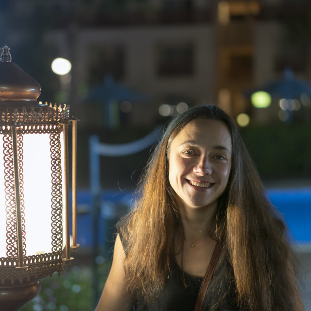 "Young woman near a large lantern on the background of a night hotel" stock image
