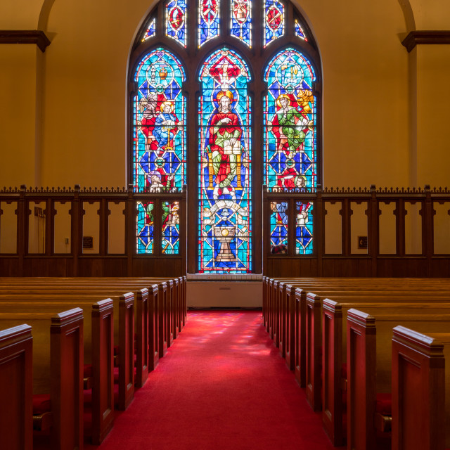 Light rays from stained glass window light up church aisle License