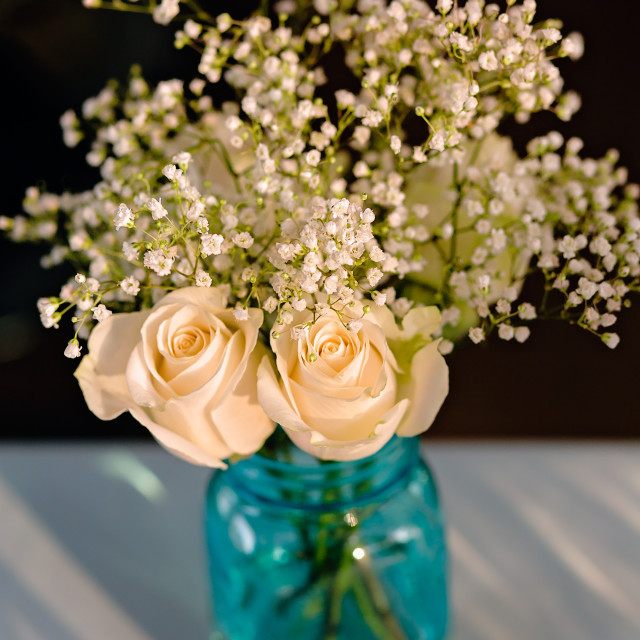 "Bouquet of White Roses and Babies Breath in a Glass Vase at a Wedding Reception" stock image