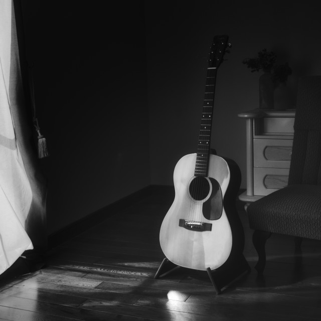 "Black & white photo of acoustic Spanish guitar on a stand in the moody..." stock image