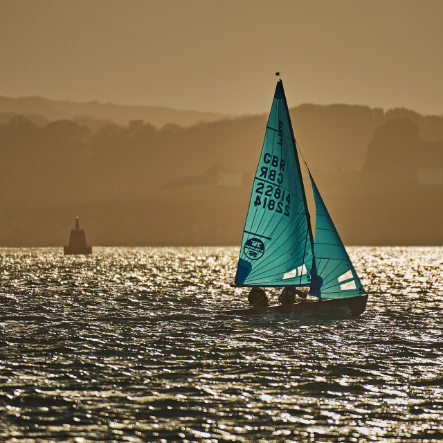 "Sailing dinghy at sunset" stock image