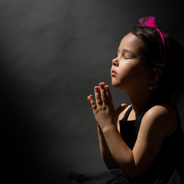 Little girl praying, isolated black background License, download or