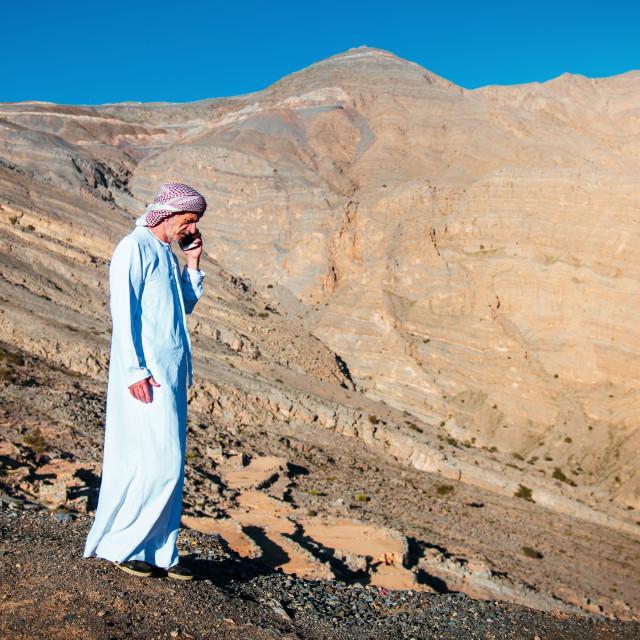 "Arab man using phone with sandstone mountain background of the U" stock image