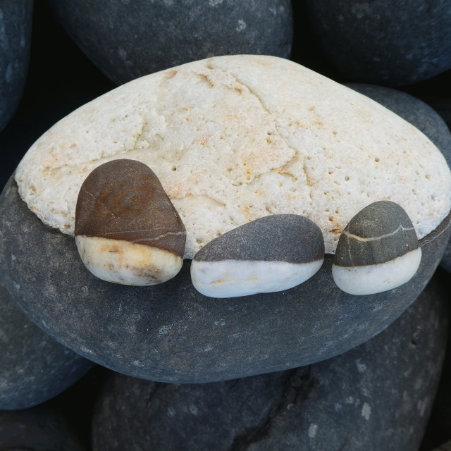 "3 small beach pebbles on one big pebble" stock image