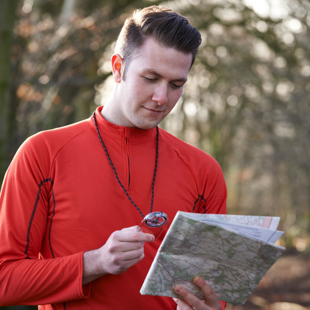 "Man Orienteering In Woodlands With Map And Compass" stock image