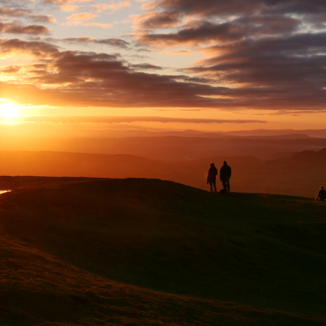 "Walkers watching the sunset and Moonrise, at British Camp, on the Malvern Hills, near Ledbury, Herefordshire, England, UK" stock image