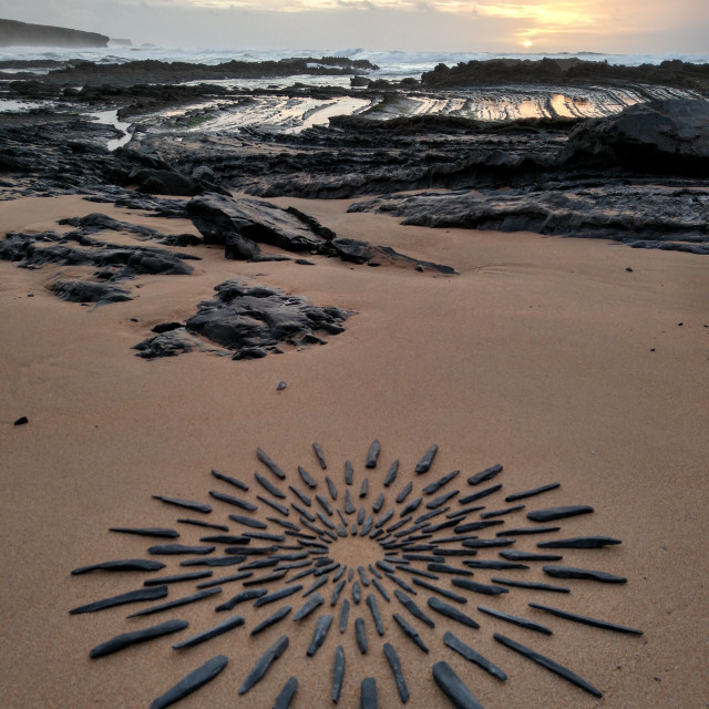 "sun made of stones on beach sand" stock image