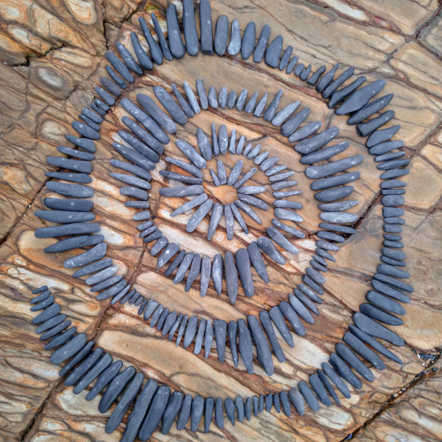 "Pulsating stone spiral on beach rocks" stock image