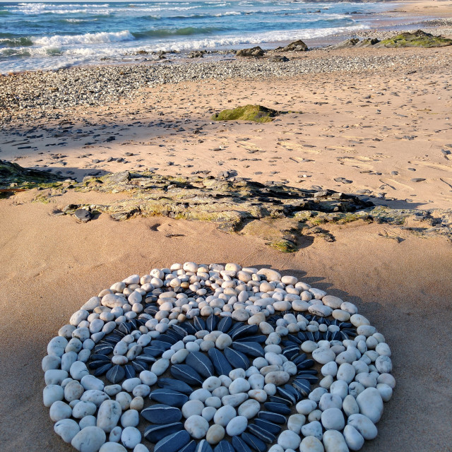 "Black stone serpent in a white beach pebble circle" stock image