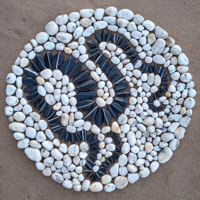 "Black stone serpent in a white beach pebble circle" stock image