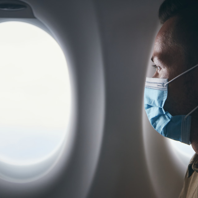 "Man wearing face mask inside airplane during flight" stock image