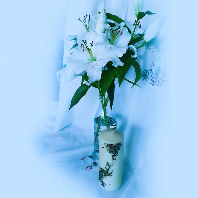 "White Lily flowers in. a glass bottle and a white candel" stock image