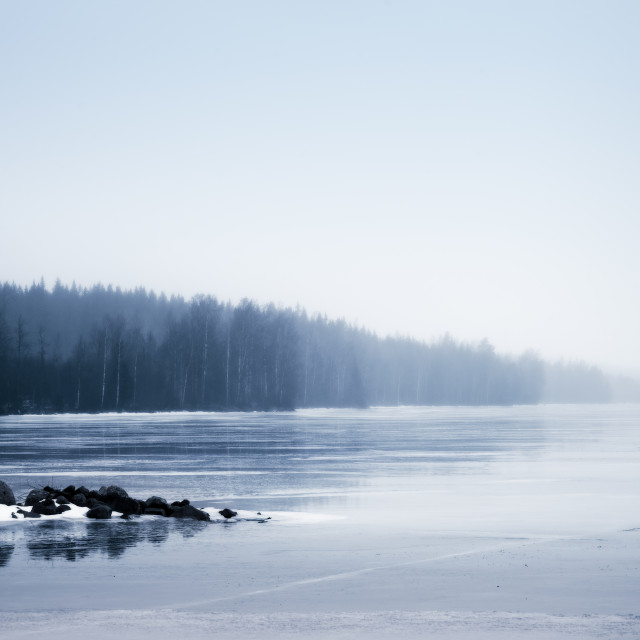 "Snowy rocks on foggy lake" stock image