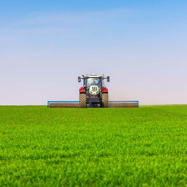 "Tractor with a roller tillage on spring field. Soil rolling supports germination and is the basis for good harvesting, organic farming and agronomy" stock image