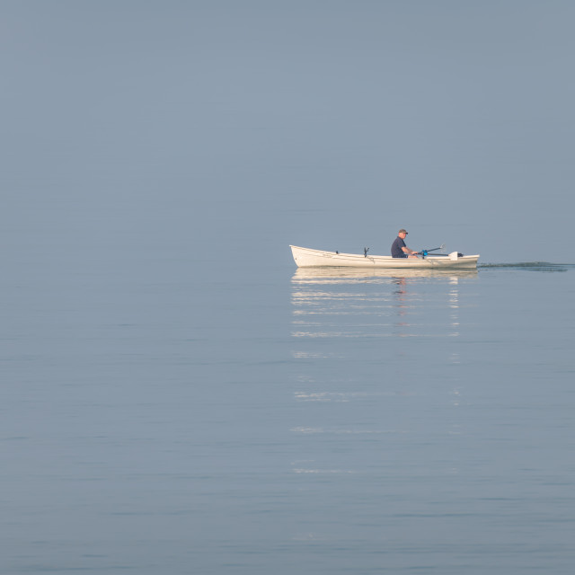 "A man rowing a boat in still waters in the mist of the Firth of Forth, Edinburgh, Scotland" stock image