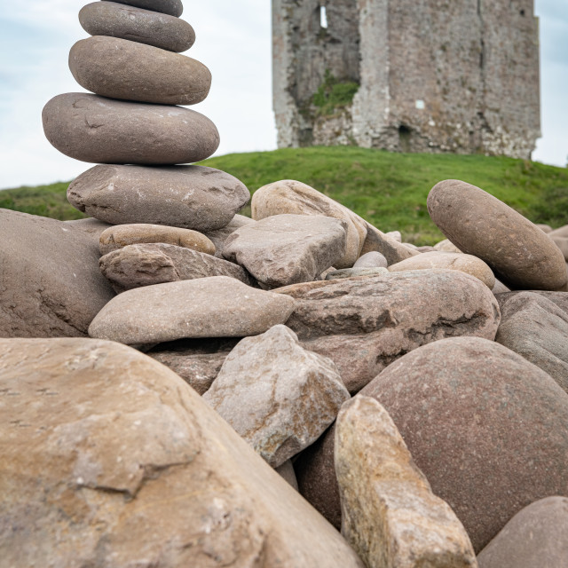 "A small rocky cairn on the rocky sea wall at Minard Beach with the remains of Minard Castle defocused in the back, County Kerry, Ireland" stock image