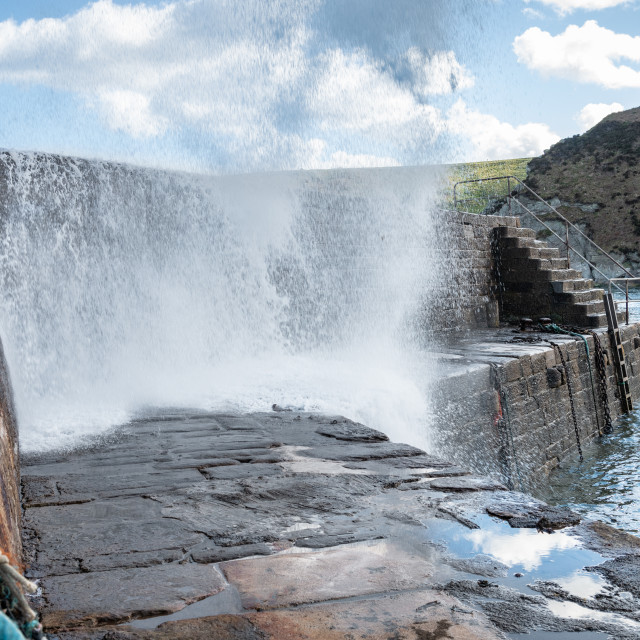 "Sea water waves coming over the harbour wall at Cove Harbour in the Scottish Borders" stock image