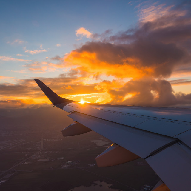 "Airplane flight in sunset sky over ocean water and wing of plane. View from the window of the Aircraft. Traveling in air." stock image