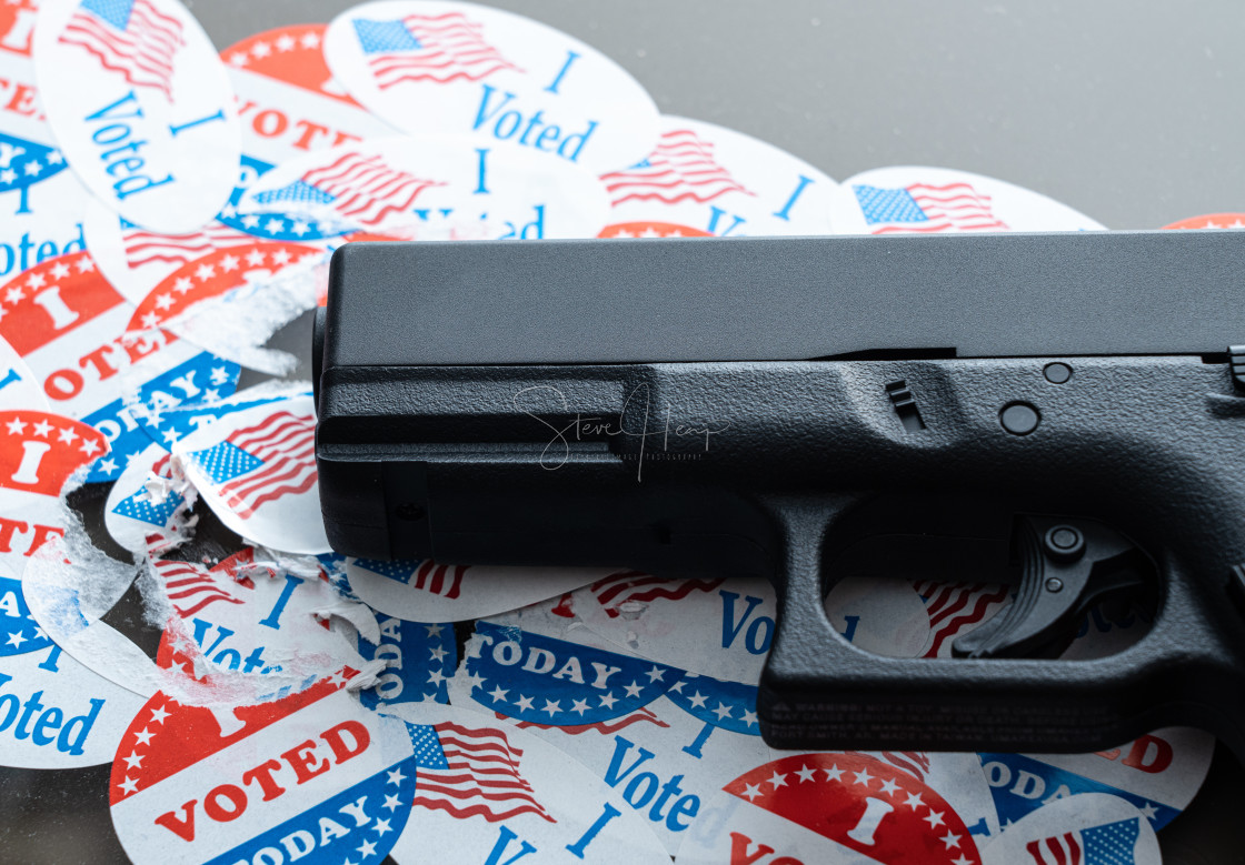 "Many torn voting campaign buttons with handgun as concept for for voter..." stock image