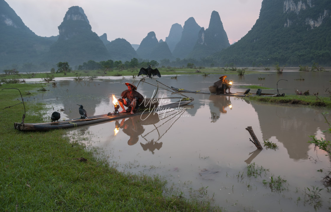 "Two Cormorant Fishermen Wait in the Twilight with Their Fires" stock image