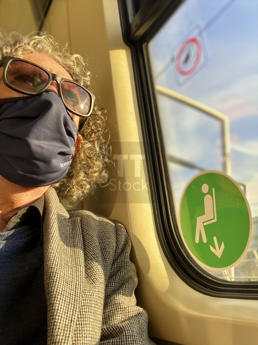 "Mature older man traveling on a commuter train during Corona epidemic wearing washable face mask." stock image