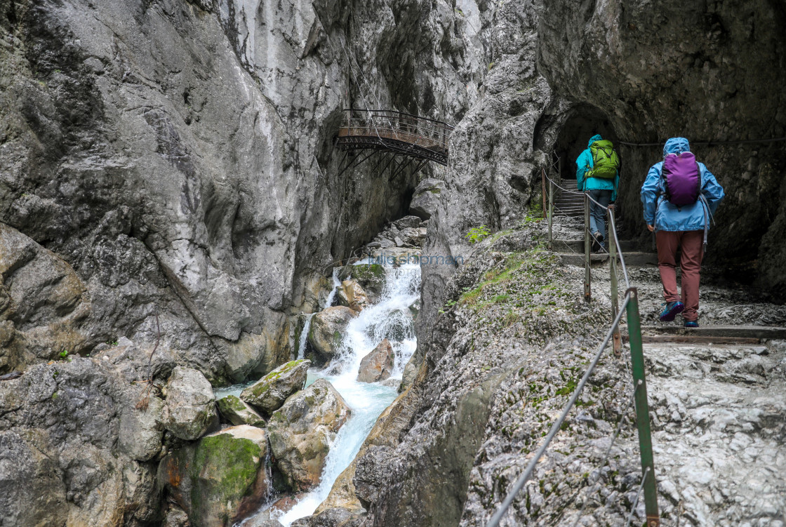 "Two women in rain gear climb the steps along a steep wet trail in the Alps outside of Garmisch, Germany. Climbing Trails in the Alps" stock image